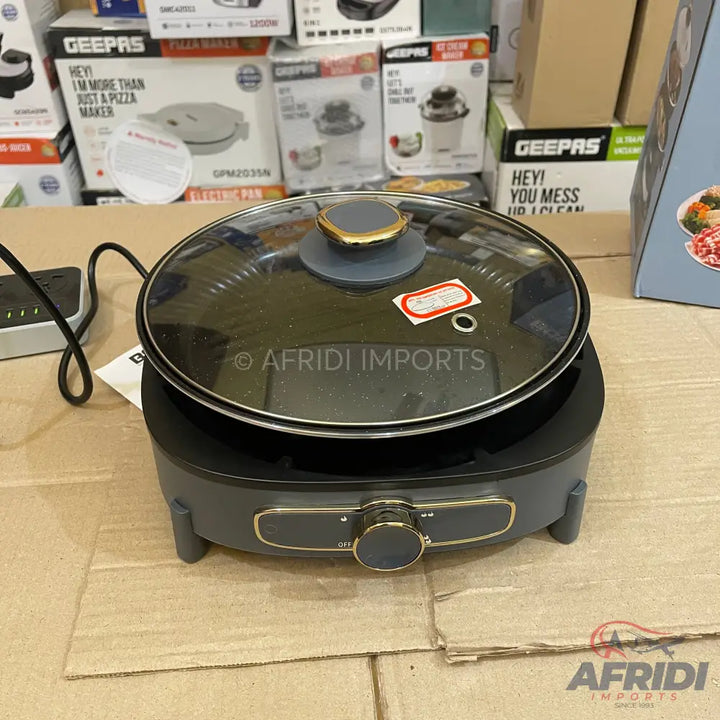 Dark gray electric cooking pot with a glass lid and gold-accented control knob.