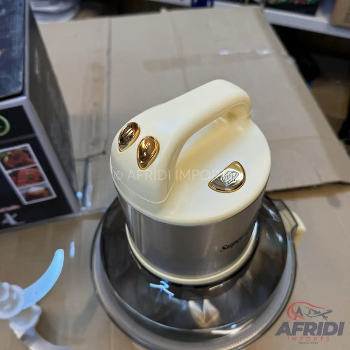 A cream and silver electric food chopper with a handle and gold-colored buttons.