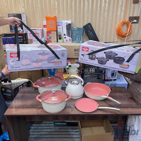 A set of pink and white cookware, including pots, pans, and a kettle.