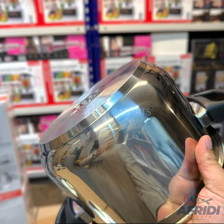 A shiny stainless steel blender jar with a handle.