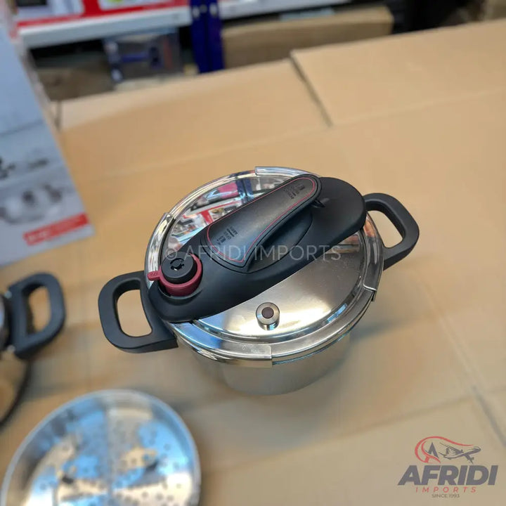Stainless steel pressure cooker with black handles and lid.