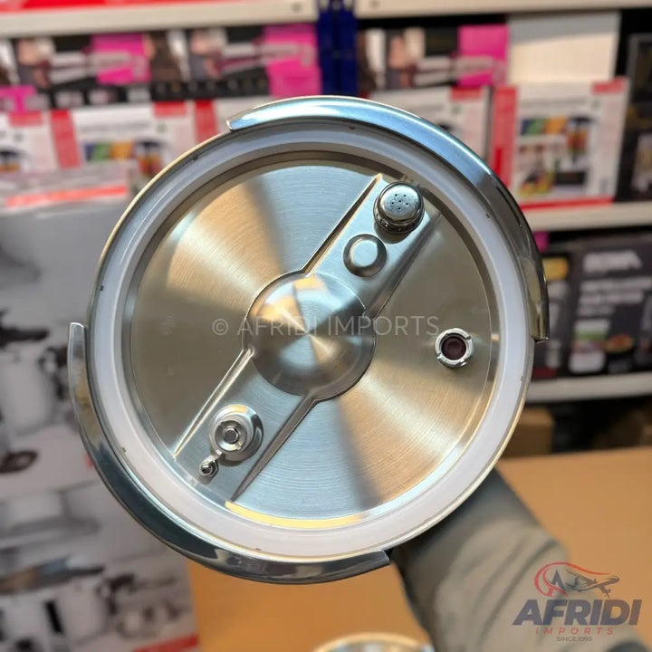 The underside of a shiny, metallic pressure cooker lid with a central rotating mechanism and two circular valves.