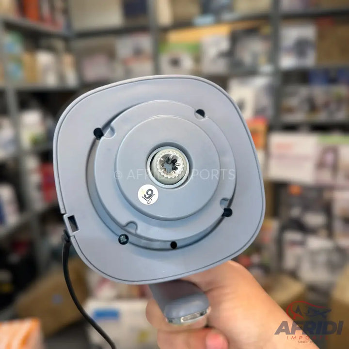 The underside of a light gray handheld blender with a central rotating coupling and a power cord extending from the base.