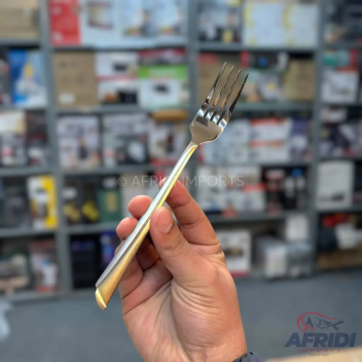 A shiny, four-tined metal dinner fork with a decorative handle.