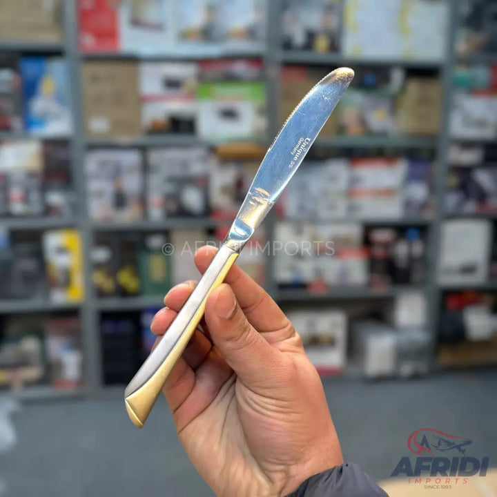 Silver and gold-colored butter knife with a pointed tip.