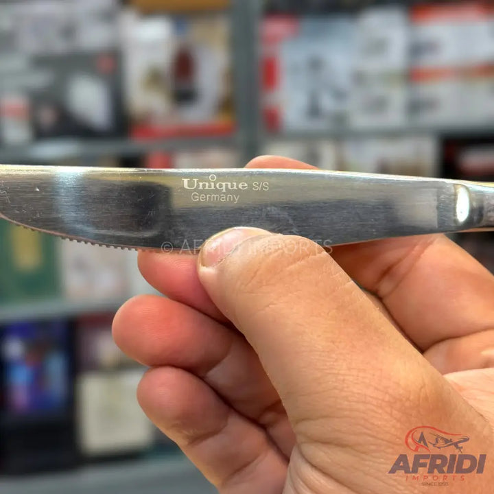 Silver-colored stainless steel dinner knife with a serrated edge.