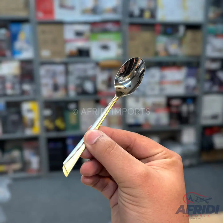 A shiny, silver-colored metal spoon with a gold-colored handle.