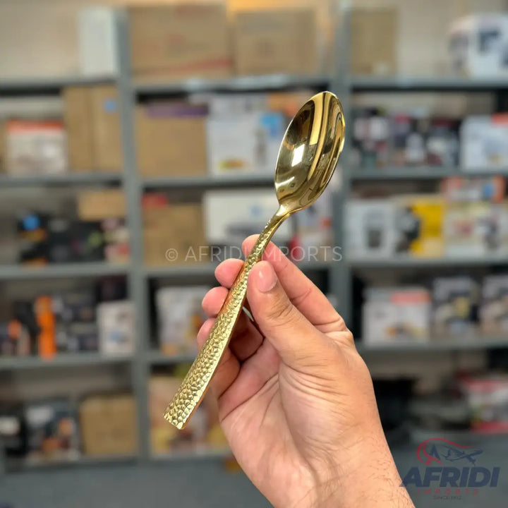 A golden spoon with a hammered texture on the handle.
