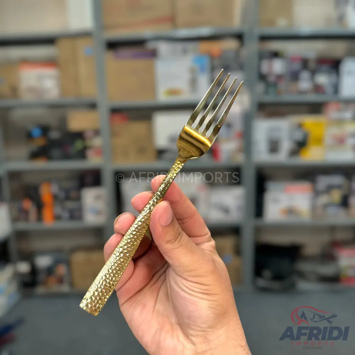 A gold-colored fork with a textured, hammered handle.