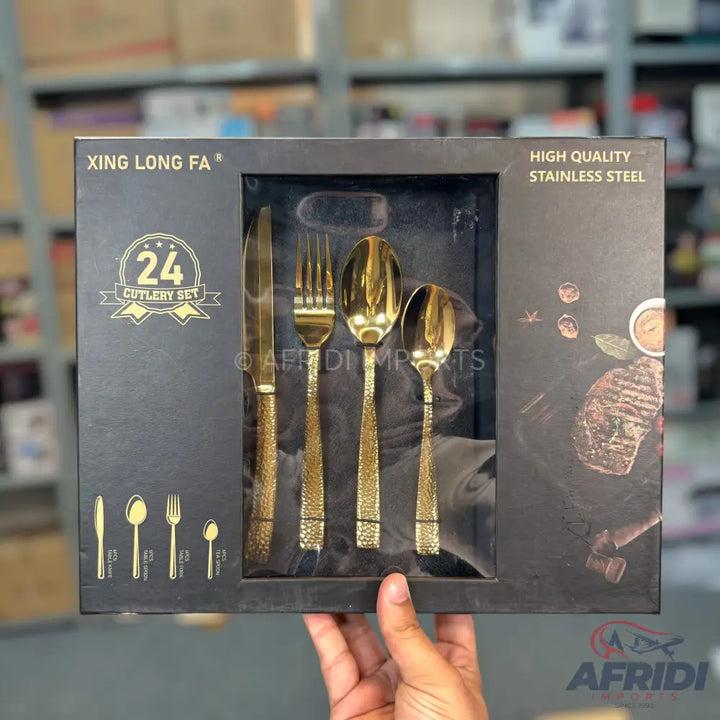 A 24-piece gold-colored, hammered-texture stainless steel cutlery set in a black presentation box.