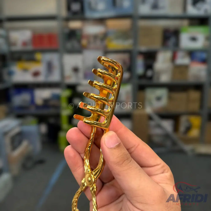 A golden pasta server with a comb-like head.