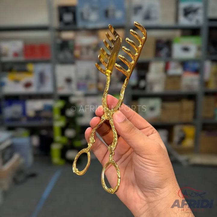 Ornate golden pasta tongs with a decorative handle.
