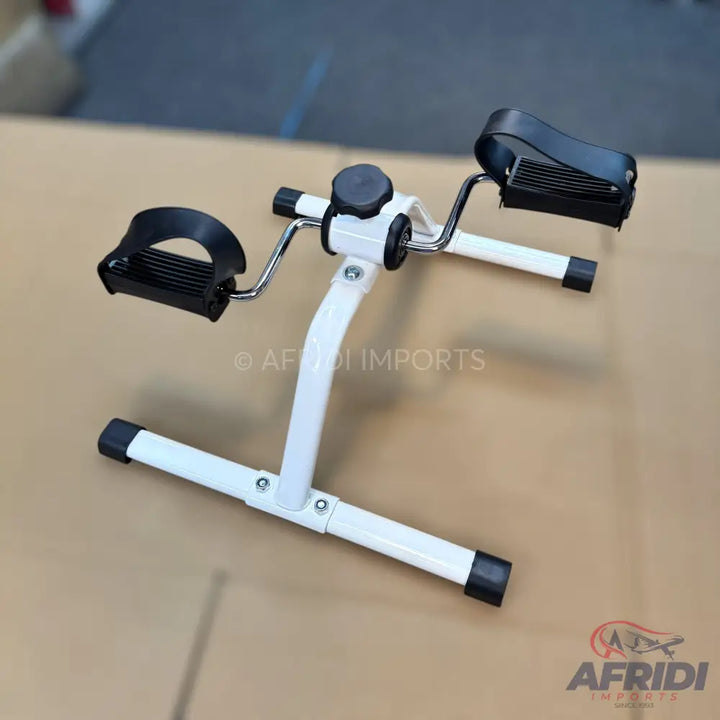 White and black portable pedal exerciser with adjustable resistance.