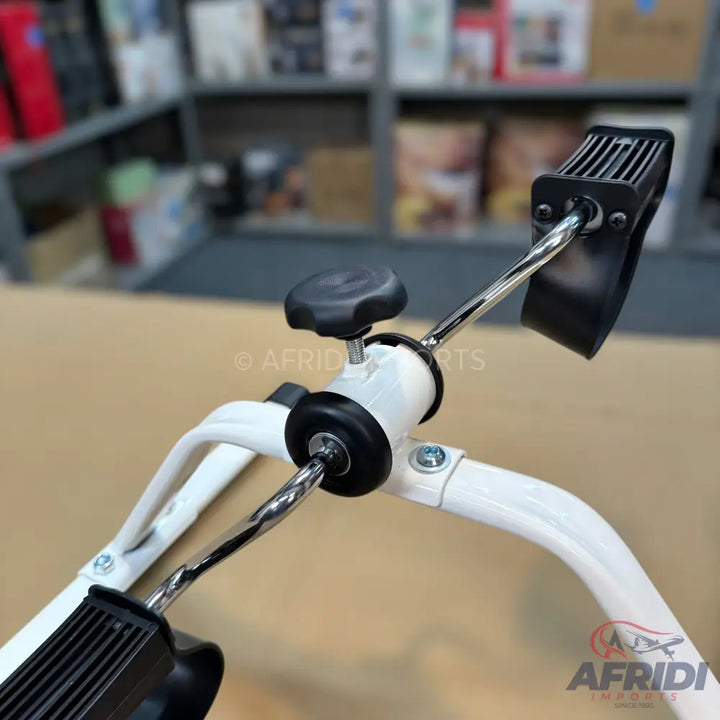 A white and black mini exercise bike with pedal straps.
