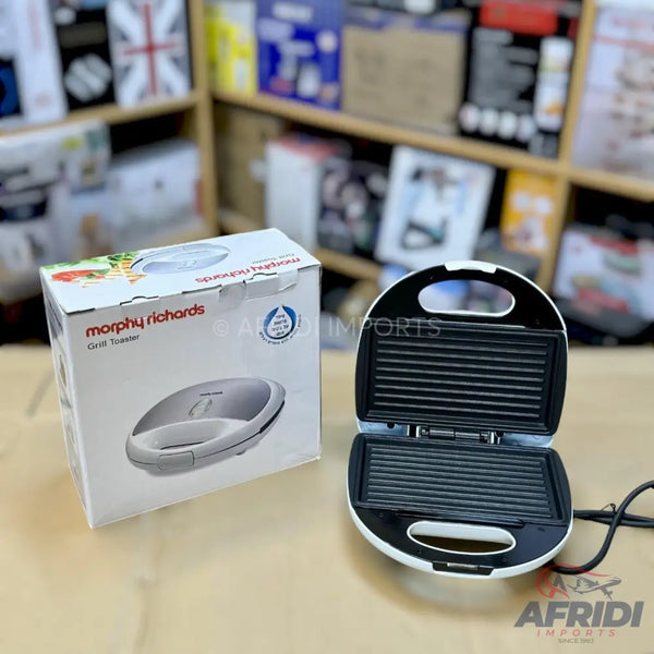 A white sandwich maker with grill plates, accompanied by its packaging box.