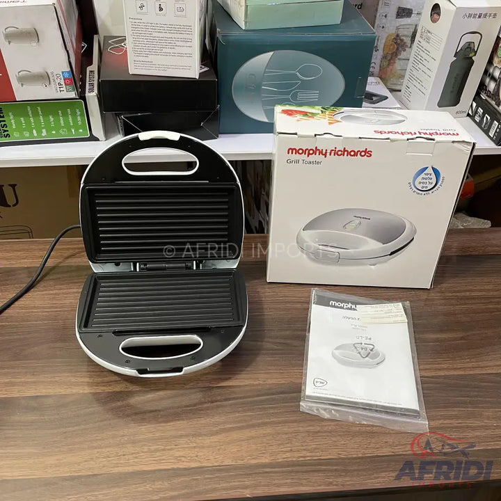 An open white and black electric grill toaster with its original packaging and manual.