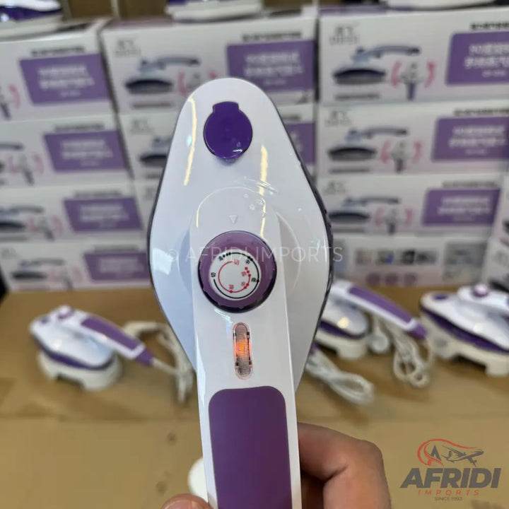 A handheld, white and purple garment steamer with a temperature dial and an indicator light.