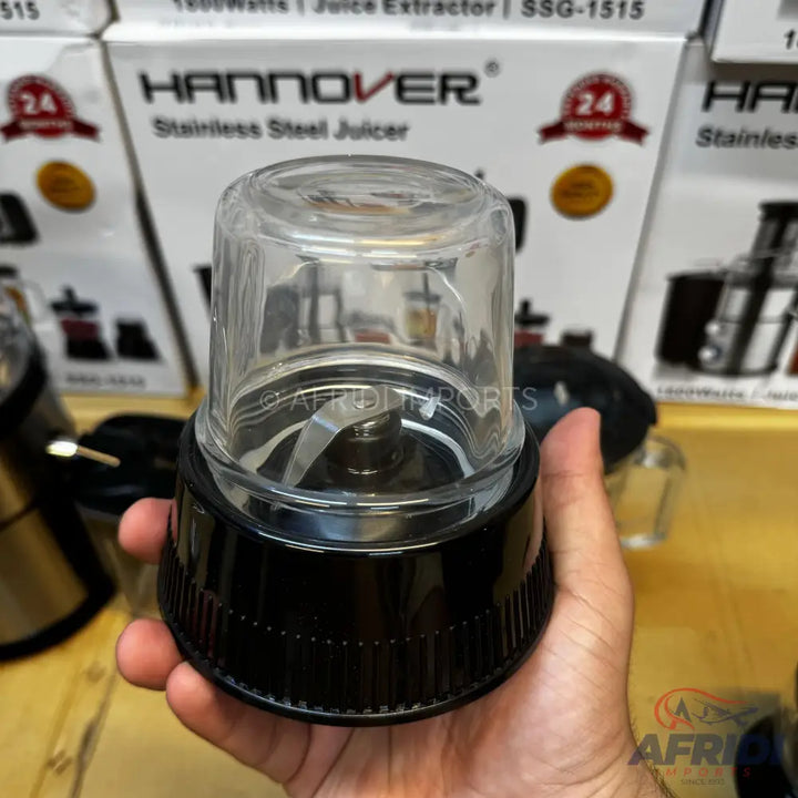 A handheld blender with a clear plastic cup and a black base, featuring a stainless steel blade.