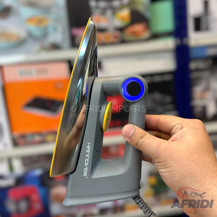 A gray and yellow travel steam iron with a blue illuminated power button.