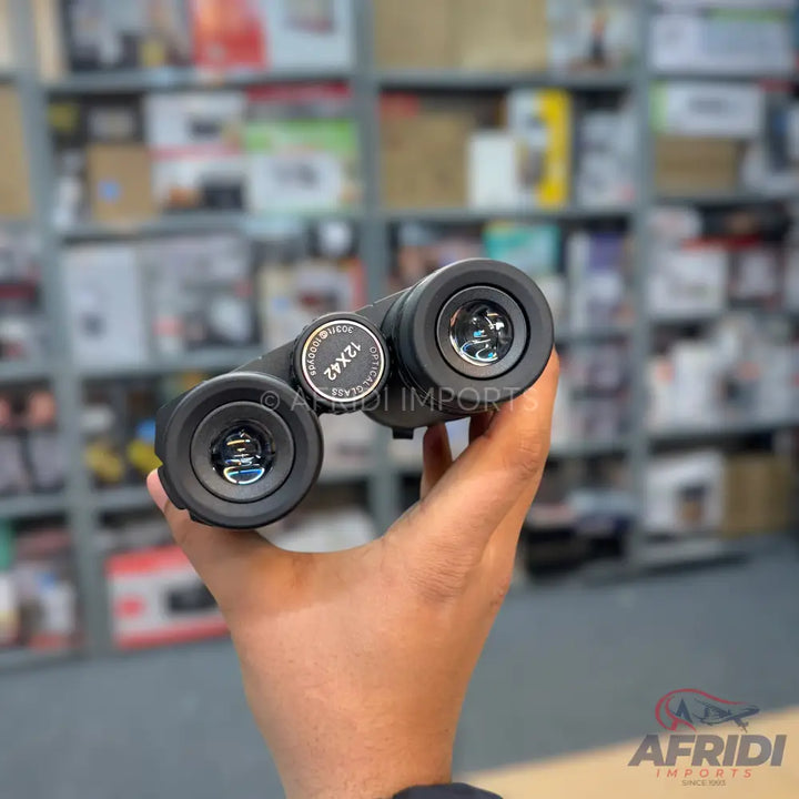 A pair of black 12x42 binoculars with clear lenses.