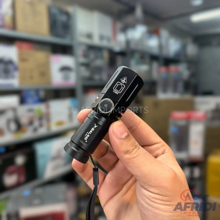 Black handheld flashlight with a wrist strap.
