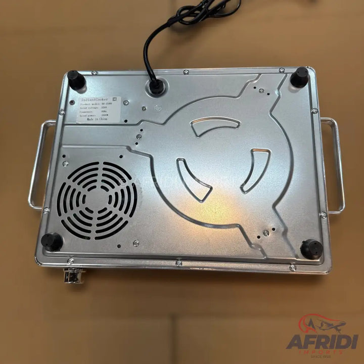 An aluminum-colored induction cooktop with carrying handles, a cooling fan, and rubber feet.