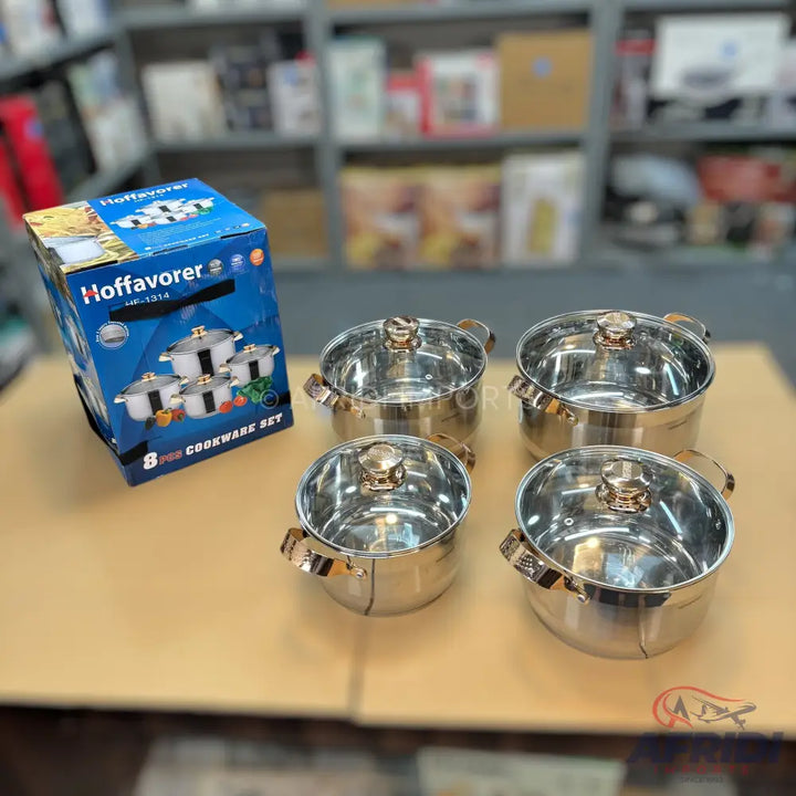 A set of stainless steel pots with glass lids and gold-colored handles.