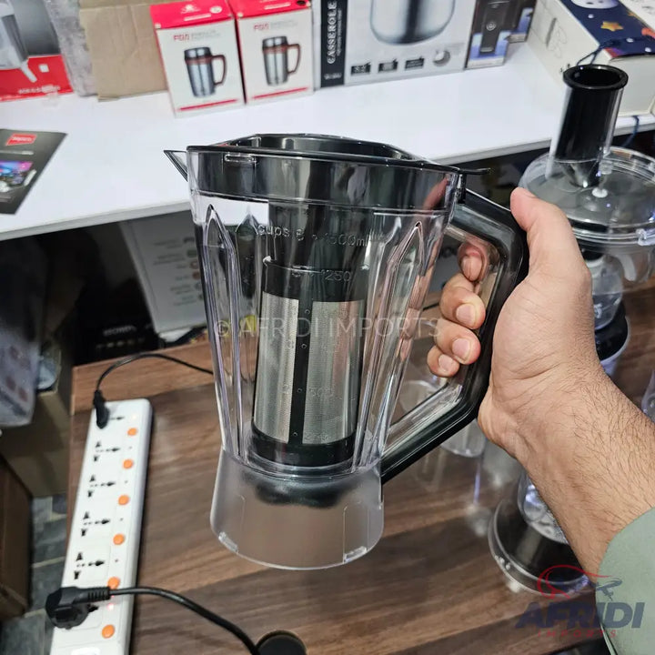 A clear plastic blender pitcher with a black handle and lid.