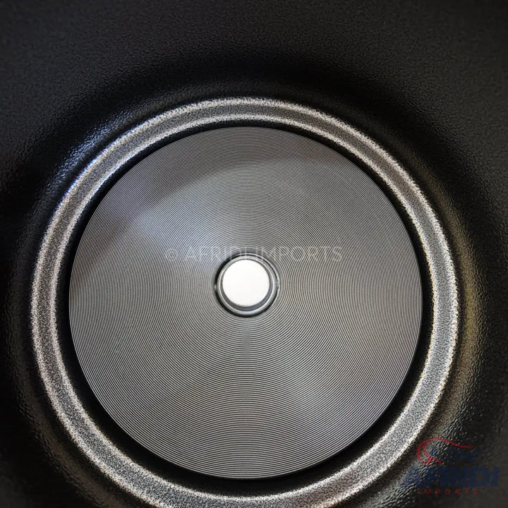 Black textured non-stick pan with a circular, ridged bottom and a central drain hole.