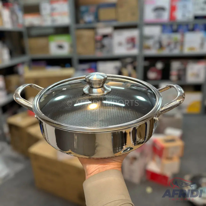 Stainless steel cooking pot with a glass lid and honeycomb-patterned interior.
