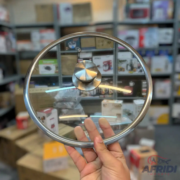 Clear glass pot lid with a metal rim and a circular metal handle.