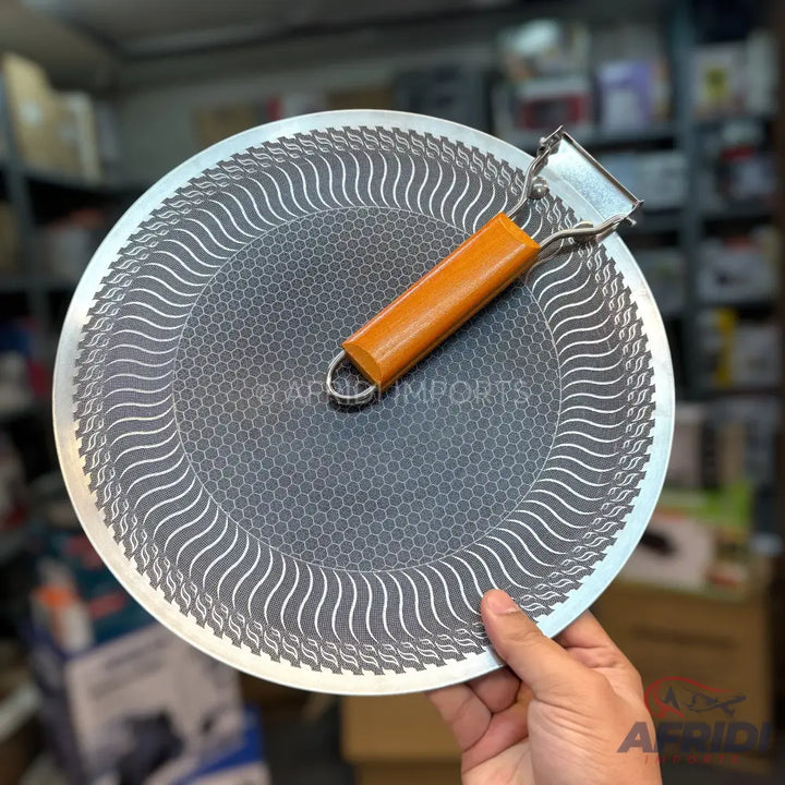 Round, flat, non-stick tawa or griddle with a removable orange handle.