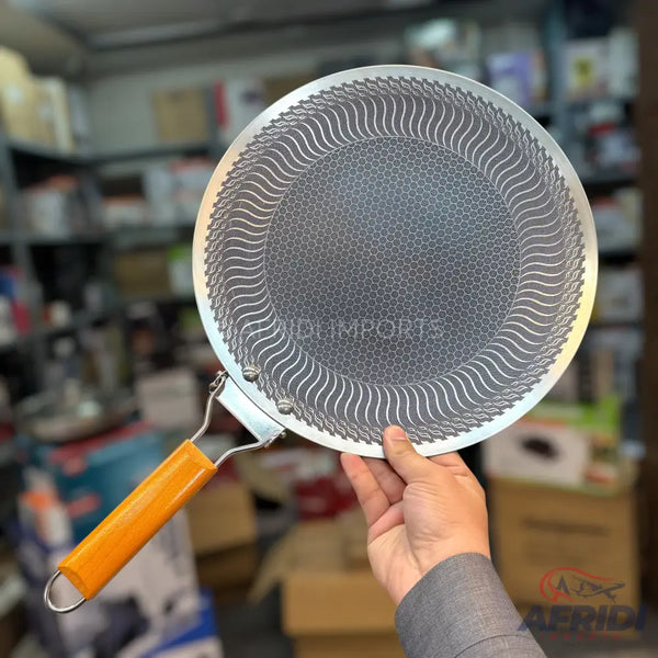 Round flat griddle with a textured surface and a single orange handle.