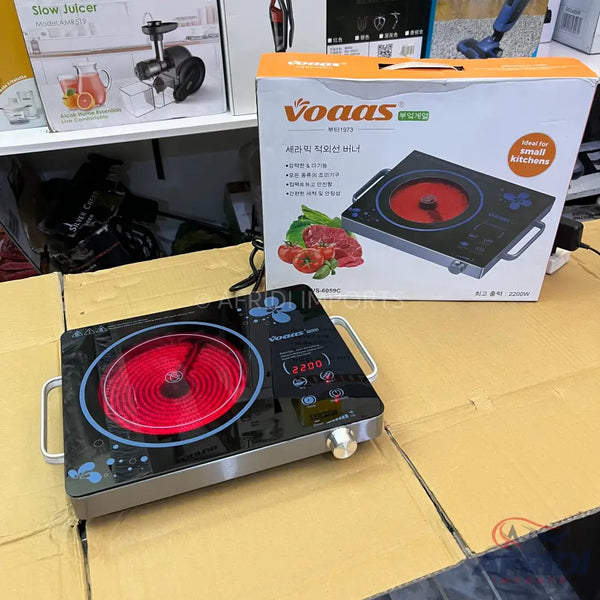 A black, portable electric cooktop with a glowing red heating element and digital controls.