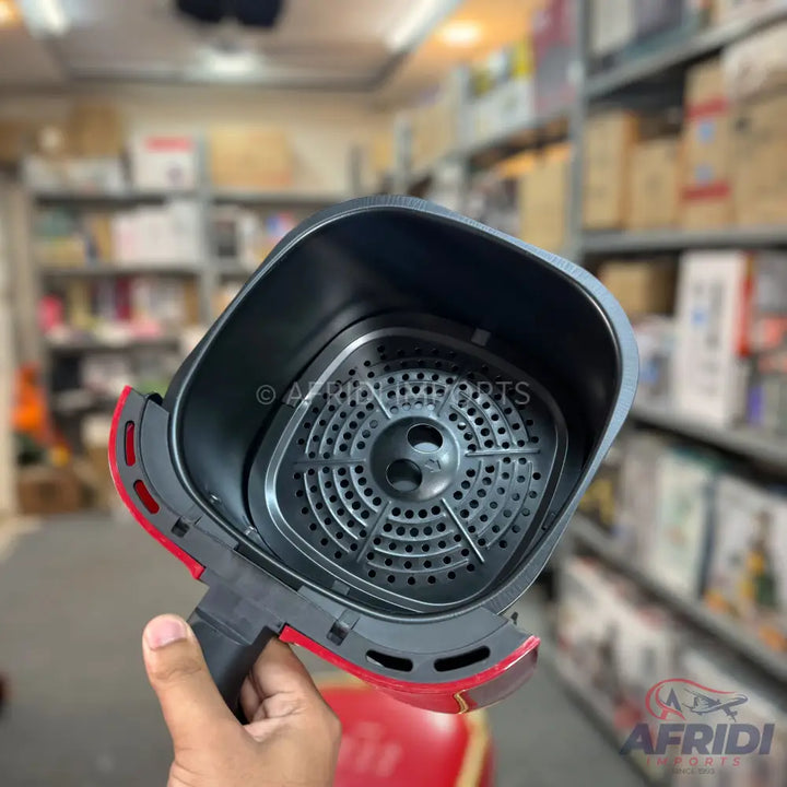 Red and black air fryer basket with a perforated bottom.