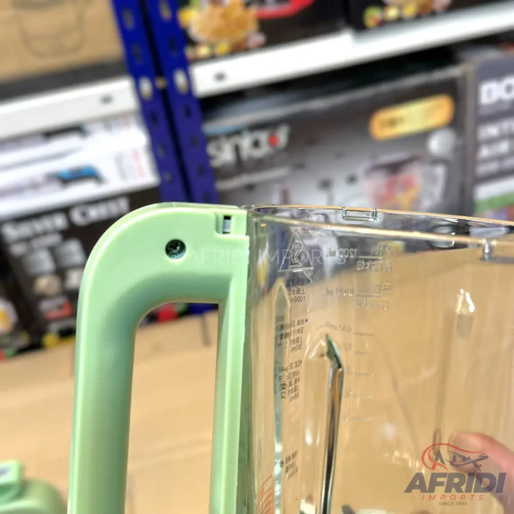 A light green blender handle attached to a clear plastic pitcher with measurement markings.