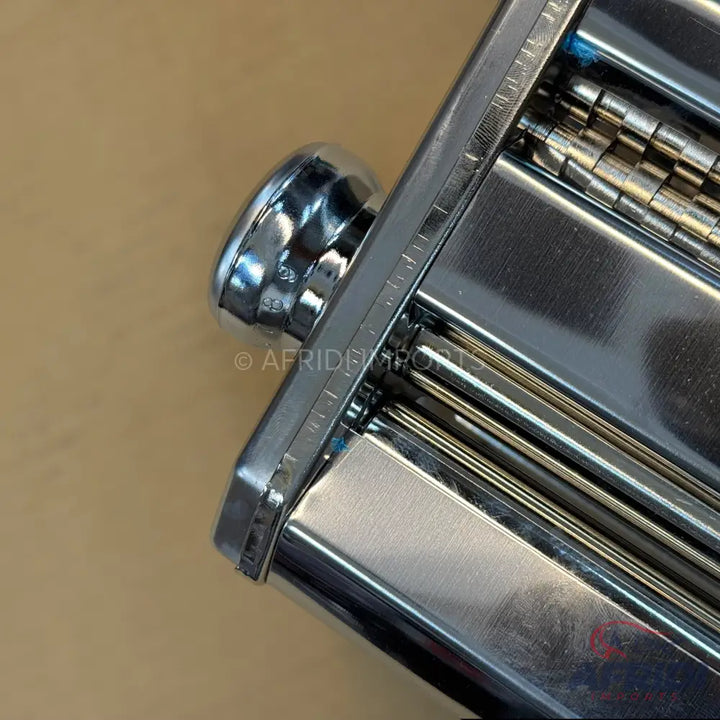 Chrome-plated manual pasta maker with adjustable rollers.
