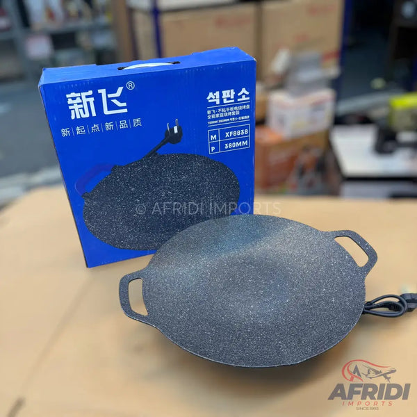 Round, electric non-stick griddle with handles.