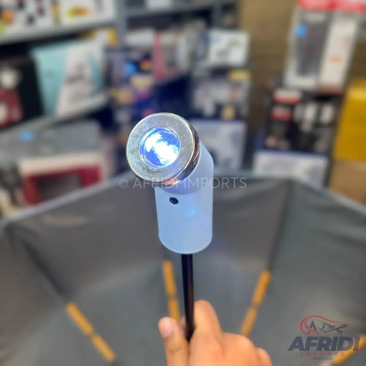 A handheld device with a light blue glowing, metallic-rimmed head, a light blue translucent body, and a black handle.