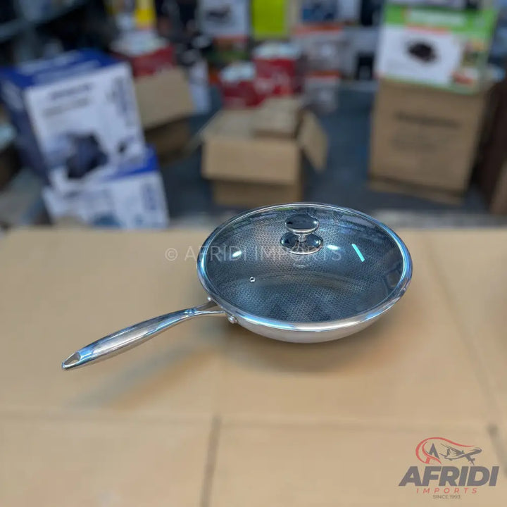 Shiny silver frying pan with a mesh-patterned glass lid.