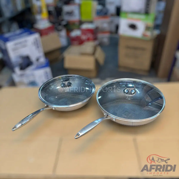 Two stainless steel frying pans with glass lids.