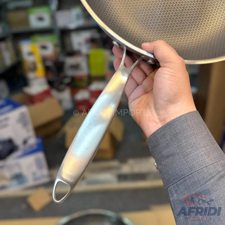 Stainless steel frying pan with a honeycomb non-stick surface and a riveted handle.