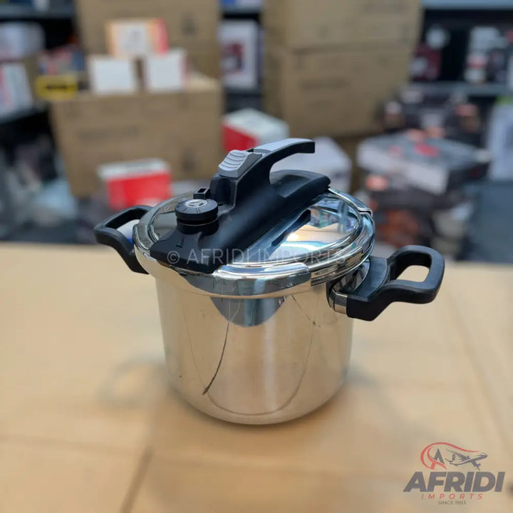 A shiny, stainless steel pressure cooker with black handles and a black lid mechanism.