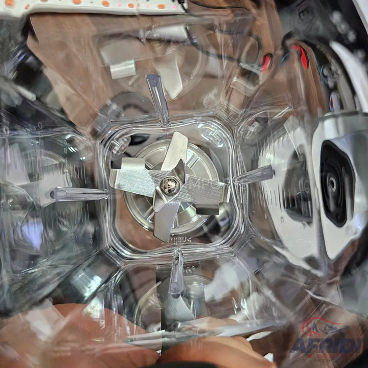 A clear plastic food processor or blender container with a four-blade stainless steel assembly.