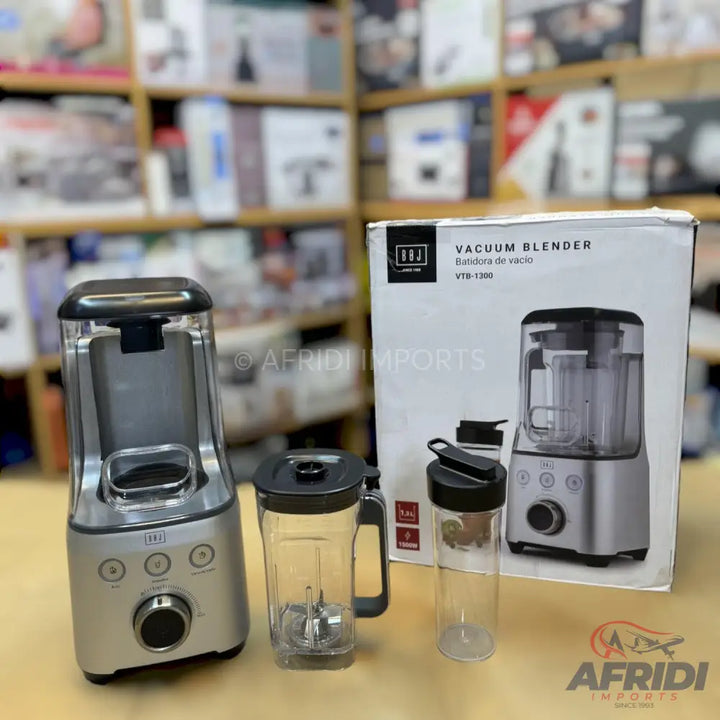 A silver vacuum blender with two clear blending cups, one with a handle and one travel-sized.