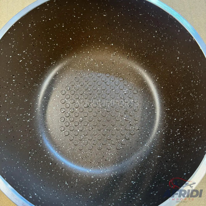 A dark-colored non-stick cooking pot with a speckled interior and a raised, honeycomb pattern on the bottom.