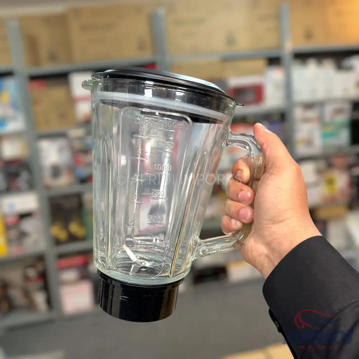 A clear glass blender jar with a black lid and base, featuring measurement markings and an internal blade.