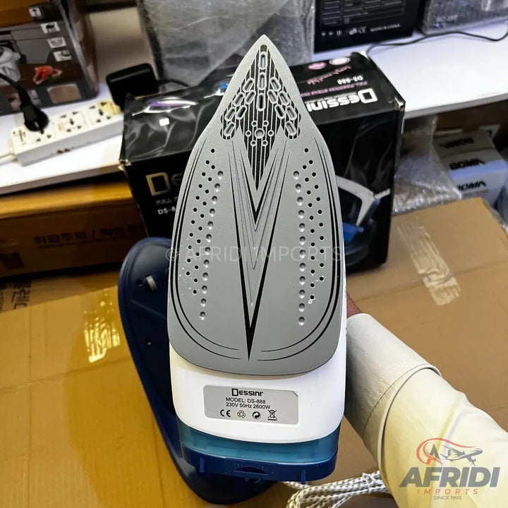 A white and blue steam iron with a gray soleplate featuring numerous steam holes and a pointed tip.