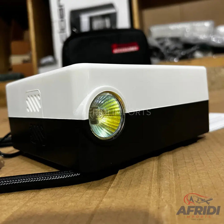 A compact, white and black portable projector with a bright lens.
