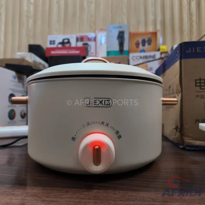 White electric hot pot with a copper-colored knob and handles.